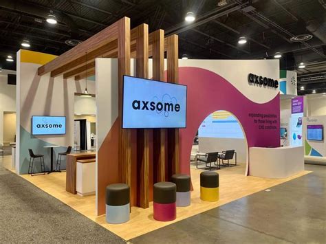 a trade show with an axsome sign on the wall and stools in front of it