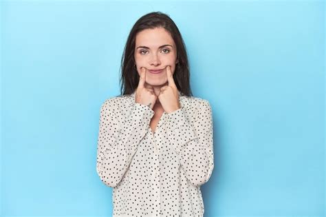 Mujer caucásica joven sobre fondo azul dudando entre dos opciones