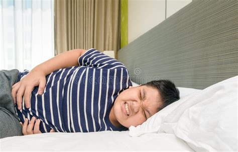 Asian Child Suffering From Stomachache And Lying On Bed Diarrhea Stock