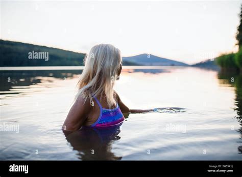 Side View Of Active Senior Woman Swimmer Diving Outdoors In Lake Stock