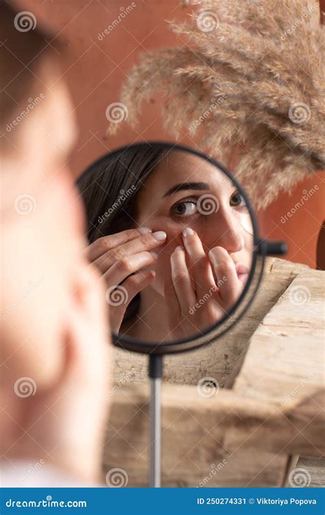 Mirror Reflection Of Woman Applying Under Eye Patch At Dressing Table