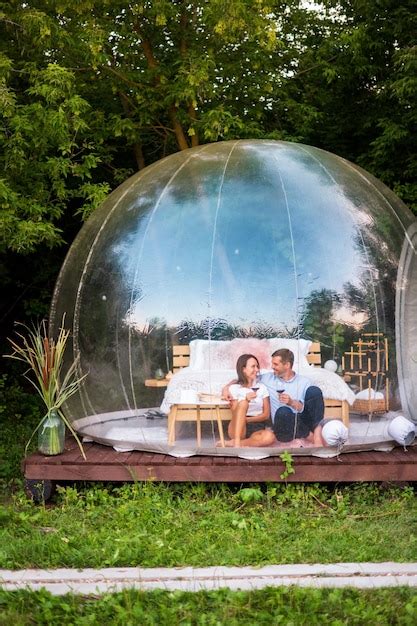 Um Casal Feliz Sentado Dentro De Uma Tenda De Bolha Transparente Em