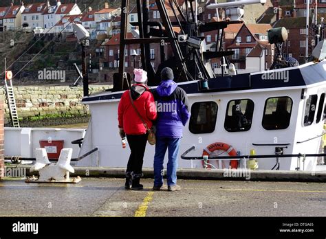 Tourist Couple Admire Large Fishing Boat Advance Moored At The Fish