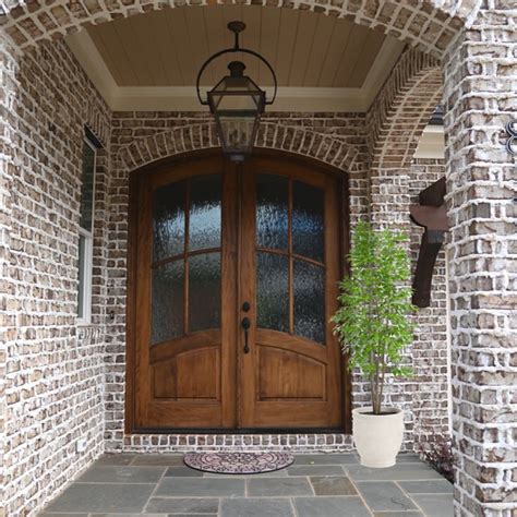 The Front Door Is Made Of Brick And Has Two Potted Plants On Either Side