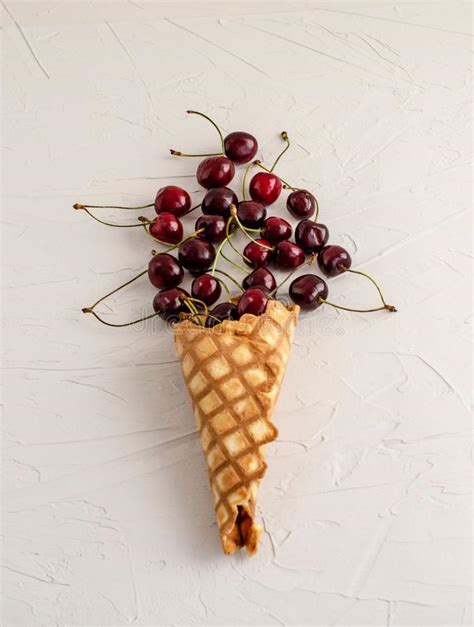 Cono De Helado Llenado De Las Cerezas En Un Fondo Concreto Blanco