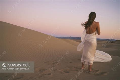Naked Female Posing On A Sand Dune Wrapped In White Cloth SuperStock
