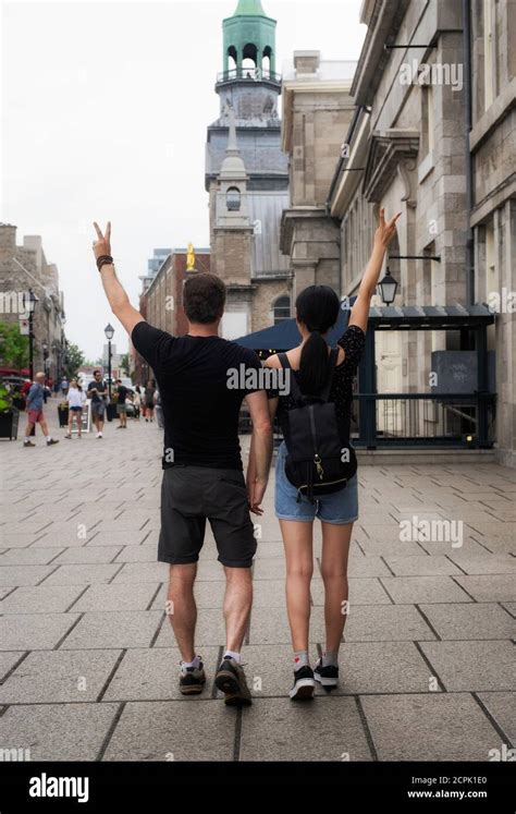 A Causasian Man And Chinese Woman Couple Flashing Peace Signs As They