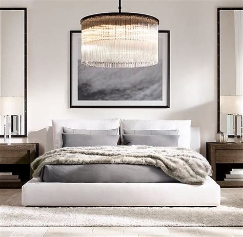 A Large Bed Sitting Under A Chandelier In A Bedroom