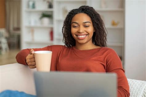 Premium Photo Black Woman Sitting On Couch With Coffee Cup Looking At