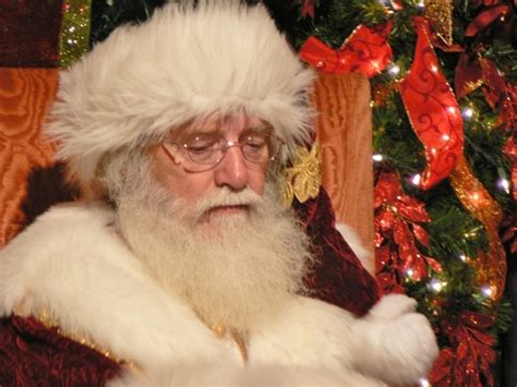 A Man Dressed As Santa Claus In Front Of A Christmas Tree