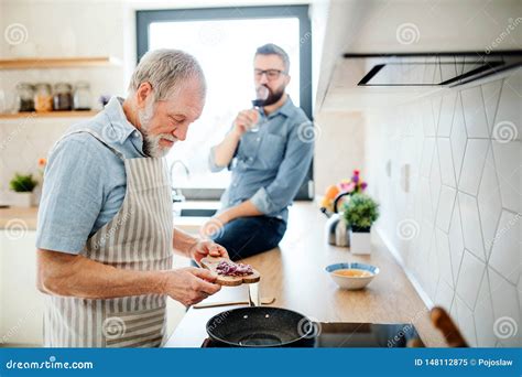 An Adult Hipster Son And Senior Father Indoors In Kitchen At Home