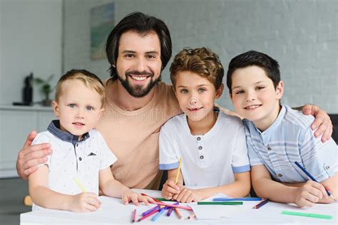 Retrato Del Padre Y De Hijos Sonrientes En La Tabla Con Los Papeles Y