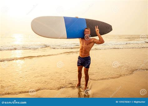 Handsome Active Sporty Man Carrying His Surfboard On The Head Surfer