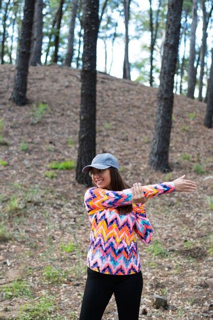 Brünette latina frau ihre arme streckt nachdem sie körperliche aktivität im wald vertikal