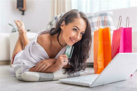 Sexy Brunette Female Shopping Online While Lying On The Floor In Light