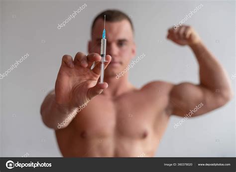 Attractive Male Bodybuilder With A Naked Torso Holds A Dope Syringe