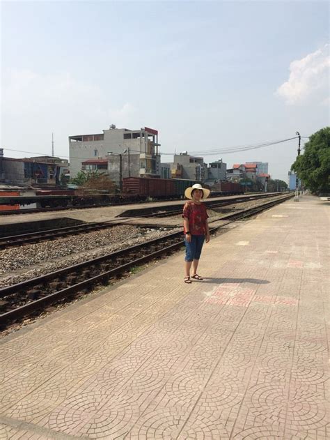 A Man In A Straw Hat Is Standing On The Railroad Tracks Near Some Train