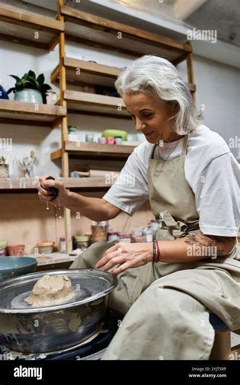 This Mature Woman Skillfully Shapes Clay On A Pottery Wheel In Her