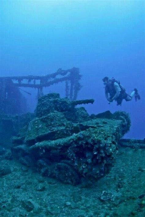 A Scuba Diver Swims Over The Wreck Of An Old Ship In The Sea Floor