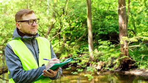 Man ecologist in the forest near a reservoir makes marks of control of ...