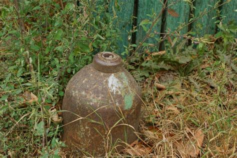 Brown Old Metal Gas Cylinder Dug Into The Ground In The Gray Dry Grass