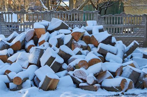 A Pile Of Firewood Covered With Snow Logs Of Firewood In The Yard In