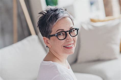 Photo Of Lovely Mature Lady Look Camera Dressed White Garment Modern Living Room Rest Enjoy