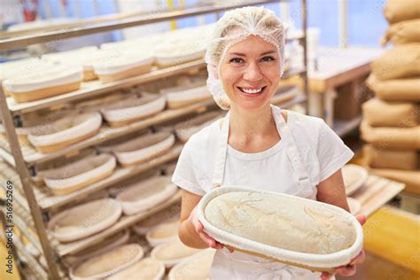 Junge Frau als Bäcker Lehrling zeigt stolz Backform mit Brot Stock