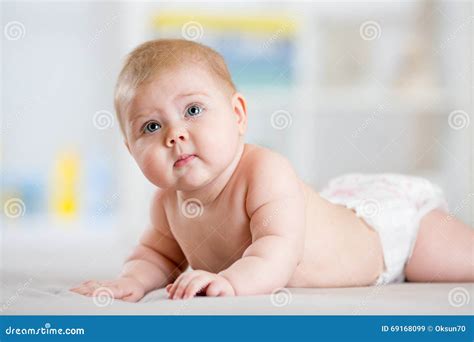 Infant Child Baby Girl In Diaper Lying On Bed In Room Stock Image