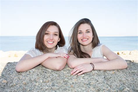 Lesbian Couple Standing At The Beach In Love Looking Into Camera Stock