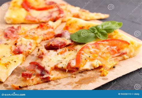 Pizza With Sausage Ham Tomato And Cheese Decorated With Basil And