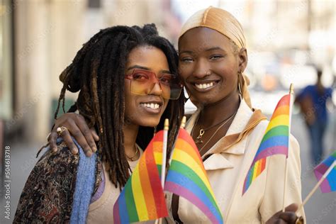 LGBTQ Same Sex Black Women Couple Waving Rainbow Flags On A City Street