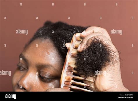 Combing black afro curly hair with shrinkage, using a wide tooth comb ...