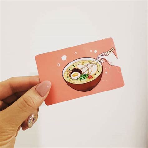 A Hand Holding Up A Pink Card With An Image Of A Bowl Of Soup On It