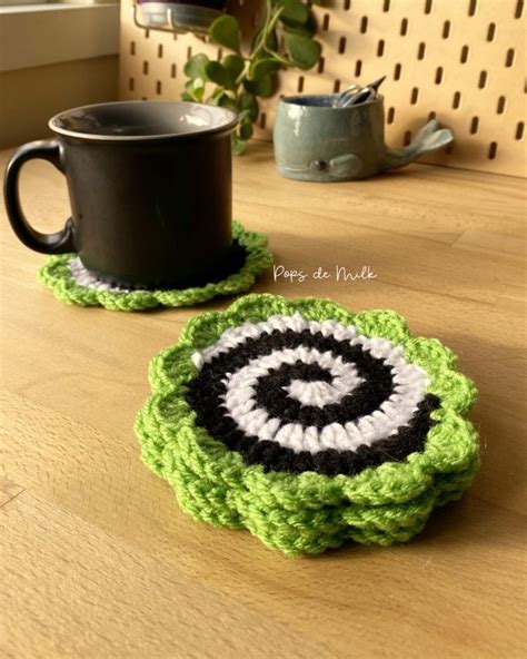 Two Crocheted Coasters Sitting On Top Of A Wooden Table Next To A