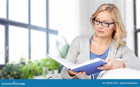 Libro Y Sentada De Lectura De La Mujer En El Sof Imagen De Archivo