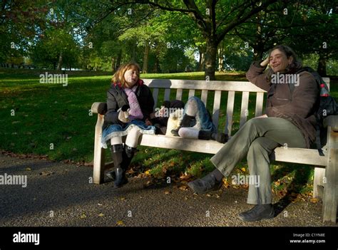 Mother And Daughter Sitting On A Park Bench Talking And Laughing London