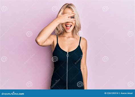 Beautiful Caucasian Blonde Girl Wearing Party Dress Peeking In Shock Covering Face And Eyes With