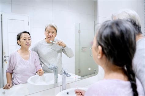 Casal sênior escovando os dentes no banheiro Foto Premium