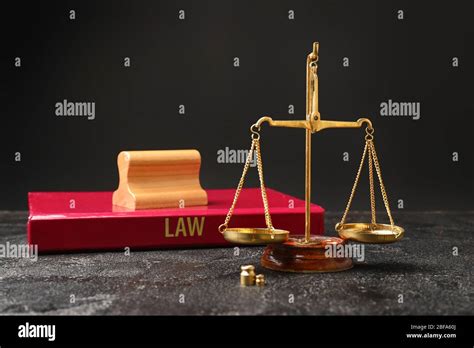 Scales Of Justice Book And Stamp On Table Against Dark Background