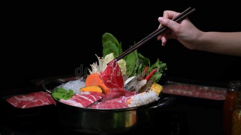 Cropped Shot Of Woman Eating Shabu Shabu In Hot Pot With Fresh Sliced Meat Sea Food And