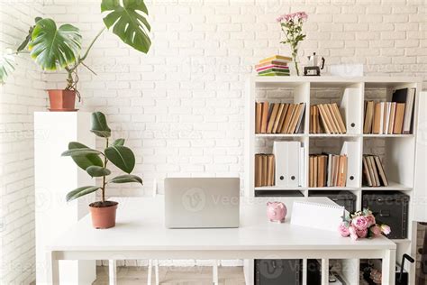 Stylish Cozy Workspace With Laptop Bookshelves And Plants