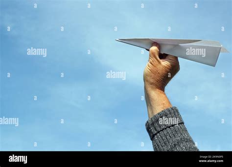 Lanzar un avión de papel o un dardo Cielo azul detrás de la mano