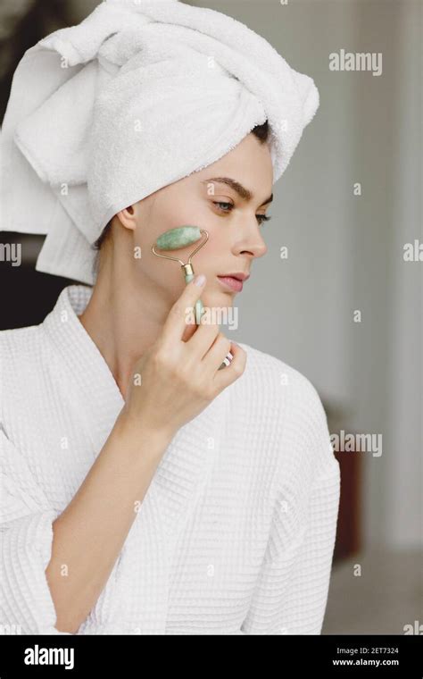 Attractive Woman With Towel On Head Getting Face Massage Using Jade