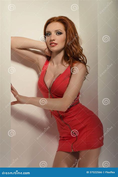 Het Sexy Roodharigevrouw Stellen In Een Rode Kleding Stock Foto Image