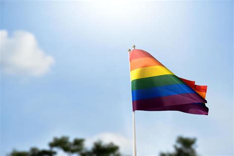 Pride Rainbow Lgbt Gay Flag Holding In Hand And Being Waved In The Breeze Against Blue Sky