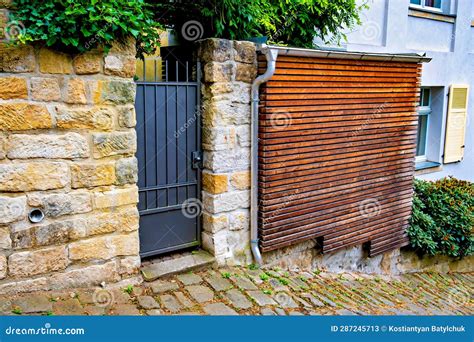 Iron Gate With Wooden Slatted Door On The Side Of Brick Building In