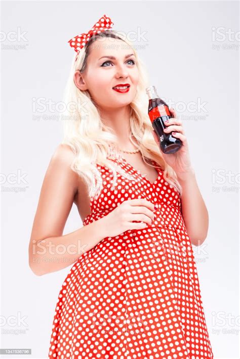 Portrait Of Smiling Blond Girl In Pinup Style Posing With Bottle Of