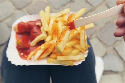 Premium Photo Close Up Of Person Eating Currywurst