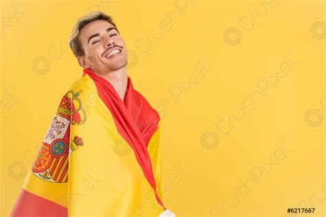 Feliz hombre gay envolviendo con una bandera nacional española foto de stock Crushpixel